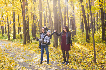 Fototapeta premium Family, fall, people concept - mixed race young family walking in park on in autumn day
