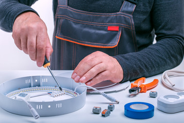 Obraz premium Electrician.The electrician repairs the ceiling lamp on the table.