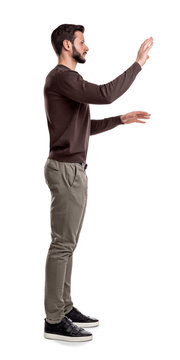 A bearded man in casual clothes stands still in a side view and used both hands to touch invisible digital screen.