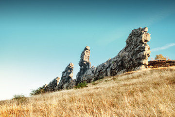 Sand stone rock pillars in a colorful landscape park at beautiful sunset light. Sandstone rock formation Teufelsmauer (Devil's Wall) in Blankenburg, National park Harz in Germany, Harz Mountains.