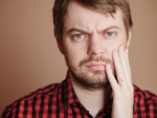 Sad young man, portrait on the beige background.