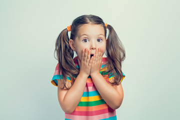 shocked or surprised beautiful cute little girl closing her mouth with hands