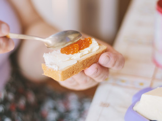 Woman spread caviar on a sandwich.
