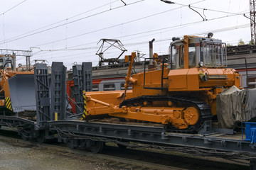 heavy orange bulldozer stands on the flatcar of the train for accident recovery work