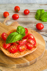 Fresh tomato bruschetta with basil on wooden background.