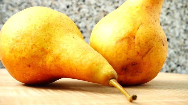 Pears on a wooden kitchen board.	Shooting in the movement.
