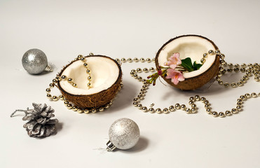 Creative layout of coconuts, concept of New Years holiday.Decorative Garland and silver balls on pink background, Christmas decor.Top view, flat lay, copy space, closeup.