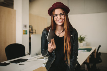 Women entrepreneur standing in office holding a tablet pc