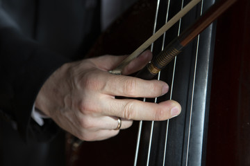 Hands of a musician playing on a contrabass closeup