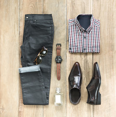 Fashionable concept, men’s clothes with loafer shoe, shirt, jeans, watch, sunglasses and perfume on wooden background. pack shots, top view