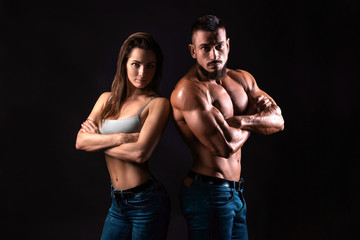 Fitness couple on a black background looking to the camera with crossed arms