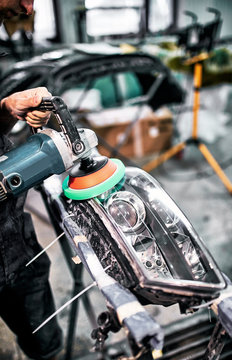  Polishing the headlights on  car with the help of power tools for maintenance.