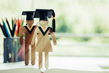 Back to School Concept, Two People Sign wood with Graduation celebrating cap on open textbook show...