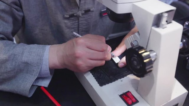 man engraving small inscription on medallions using microscope and special little scalpel. Close up