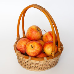 Red and yellow apples in a wicker basket. Isolated.