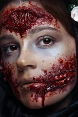 Portrait of bloody horrible scary zombie girl in a halloween festive makeup. Red eyes.