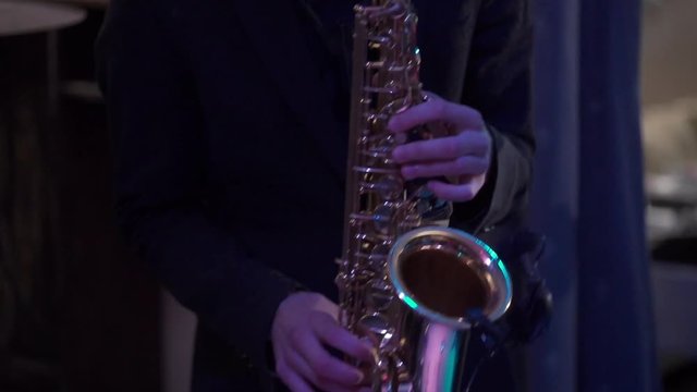 Man plays on a saxophone at the stage with band