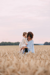 Mother and daughter in a wheat field, family portrait