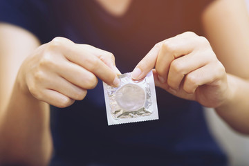 Condom ready to use in female hand, give condom safe sex concept on the bed Prevent infection and Contraceptives control the birth rate or safe prophylactic. World AIDS Day, Leave space for text. - obrazy, fototapety, plakaty