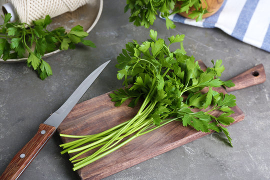 Wooden board with fresh green parsley on table