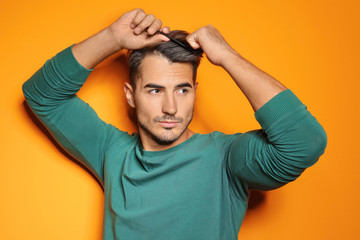Young man with comb posing on color background. Trendy hairstyle