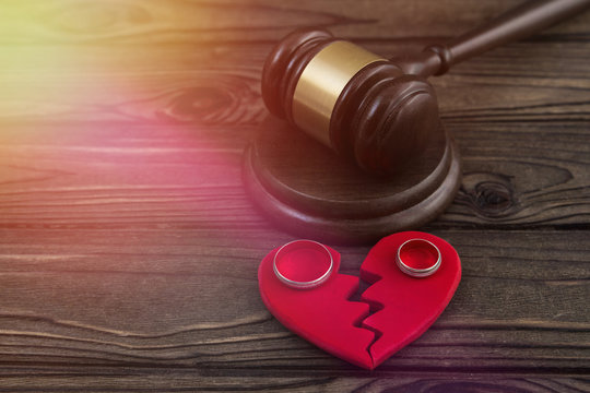 a judge's hammer, a heart, a pair of wedding rings against the background of a wooden table. divorce, family law.