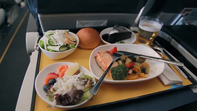 Food served on board of business class airplane on the table. Tray of food in the airplane. Tray of food on the plane, business class travel. Prepared food on the plane
