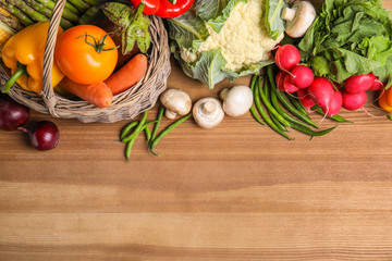 Flat lay composition with assortment of fresh vegetables on wooden table. Space for text