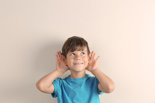 Cute little boy with hearing problem on light background