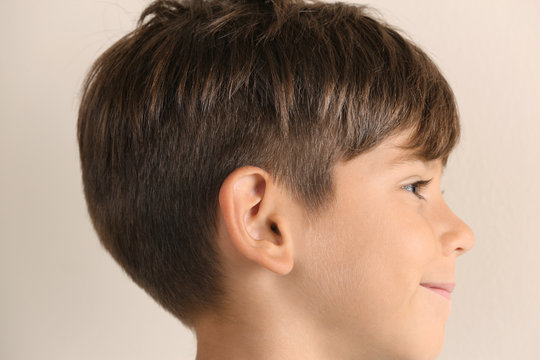 Cute little boy on light background, closeup. Hearing problem