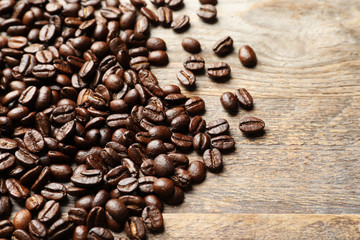 Pile of roasted coffee beans on wooden background