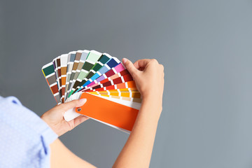 Female interior designer with palette samples on color background, closeup. Space for text