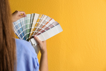 Female interior designer with palette samples on color background, closeup. Space for text