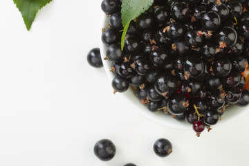 ripe juicy currant branches in a plate on white table