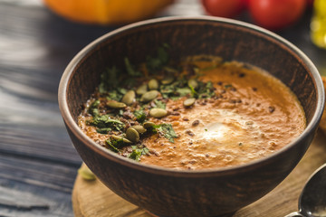 Pumpkin soup with cream and pumpkin seeds on  wooden background.