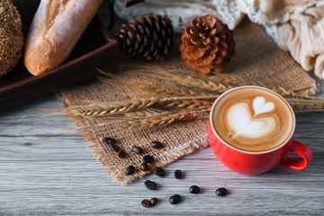 Heart coffee latte in red cup with bread.