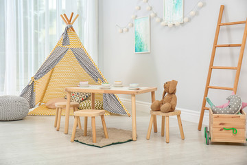 Cozy kids room interior with table, play tent and toys