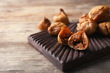 Board with dried figs on wooden table. Organic snack