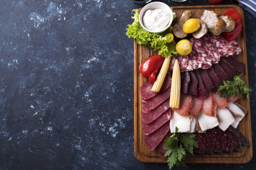 Different sausages with pickled vegetables on wooden board. Top view