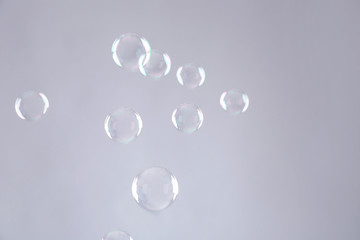 Beautiful translucent soap bubbles on grey background
