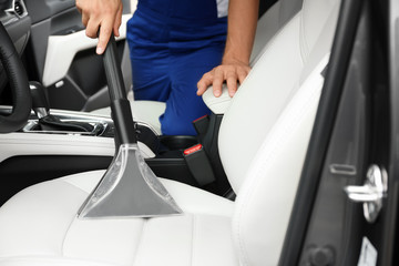 Man using vacuum cleaner in auto, closeup. Car wash