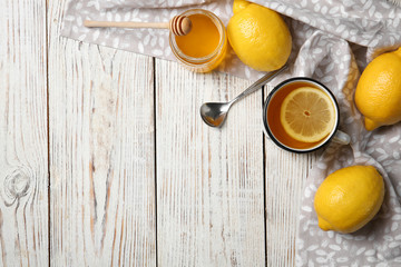 Cup with hot lemon tea and honey on wooden background, top view. Space for text