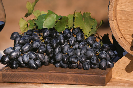 Wooden board with ripe wine grapes on table