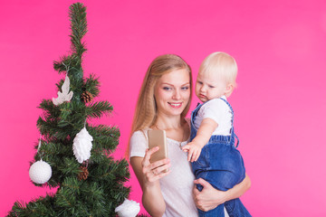 Mother and little daughter taking a selfie near Christmas tree