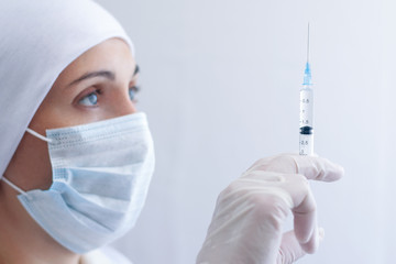 A nurse is holding a syringe with medicine at eye level.