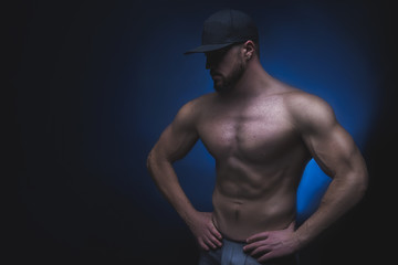 Fototapeta na wymiar Young bearded athlete in a cap on a black background. Fitness. CrossFit. Fitness model