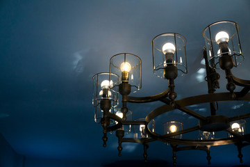 Fototapeta na wymiar Vintage light classic chandelier hanging on the blue ceiling