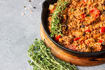 Pan of italian sauce bolognese with thyme on grey concrete background. Copy space.