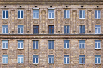 Front view on fragment of facade of a old brick residential building with windows (texture, background)