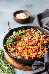 Pan of italian sauce bolognese with thyme on grey concrete background. Copy space.